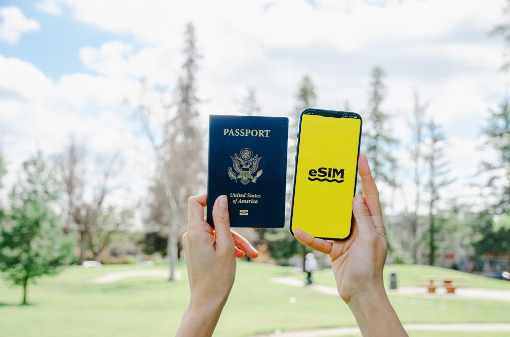 Traveler holding passport and phone displaying Saily eSIM, highlighting easy international mobile setup for trips abroad.